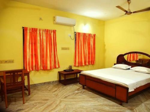 a bedroom with a bed and a desk and two windows at Smith 5BHK Villa in Puducherry