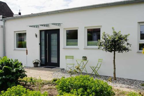 ein weißes Haus mit grünen Stühlen und einer Tür in der Unterkunft Ferienhaus Refugium in Michelstadt