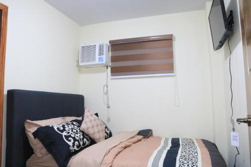 a bedroom with a bed and a window with a air conditioner at Anicia Guesthouse Units in Manila