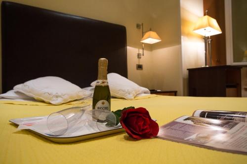 a bottle of champagne and a rose on a bed at Hotel Giolitti in Rome