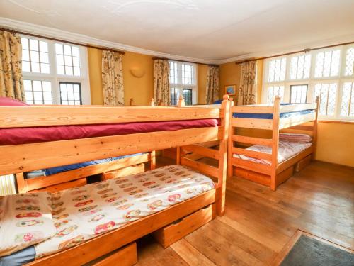 Habitación con 2 literas, suelo de madera y ventanas. en Wick Court Farm, en Gloucester