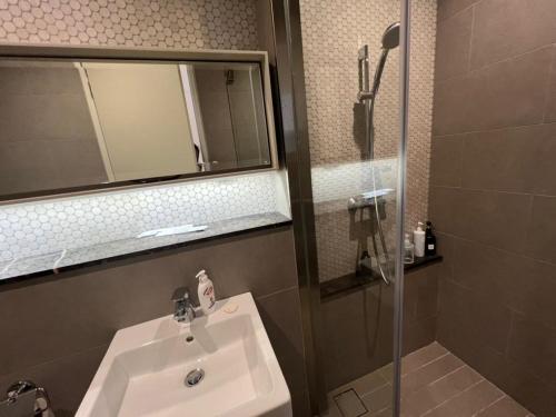 ein Bad mit einem Waschbecken, einem Spiegel und einer Dusche in der Unterkunft BBCC Apartments At Lucentia in Kuala Lumpur