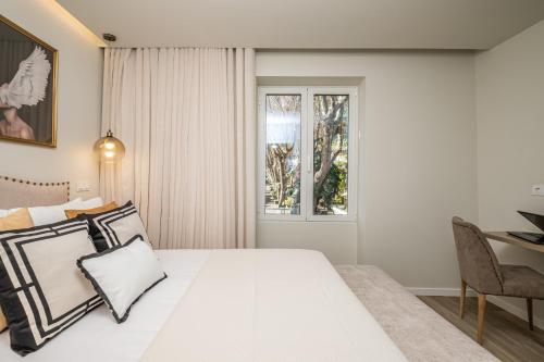 Habitación blanca con cama y ventana en Machim D'Arfet House by Madeira Sun Travel, en Machico