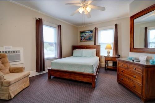 1 dormitorio con cama, silla y vestidor en Carriage House Motel Cottages & Suites en Wells