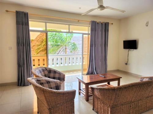 a living room with a table and chairs and a large window at Nightingale Apartments Hotel Mombasa in Shanzu