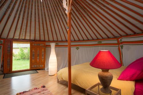 a bedroom in a yurt with a bed and a red lamp at Tiny House et yourte sous les Poiriers in Domfront