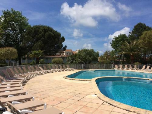 une piscine avec des chaises longues et un complexe hôtelier dans l'établissement M-Fairway 01-Moliets Duplex 6 personnes dans résidence avec piscines proche du golf, à Moliets-et-Maa