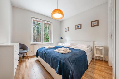 a bedroom with a bed with a blue blanket at Apartamenty Sun & Snow Ratibora Jurata in Jurata