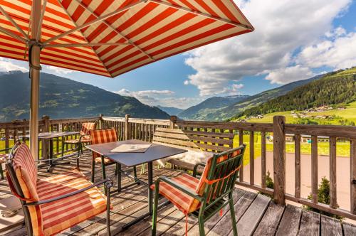 a deck with a table and chairs and an umbrella at Alpen Wohlfühlhotel Dörflwirt in Hainzenberg