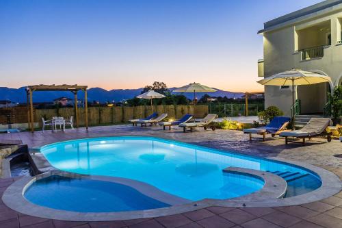 a swimming pool in a patio with chairs and a house at Villa Kampos in Vanáton