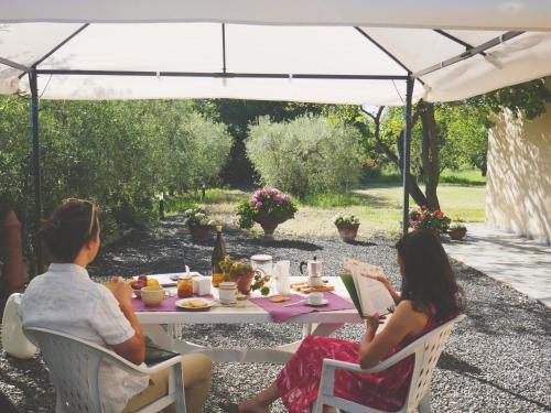 two people sitting at a table under a white umbrella at La Ripa Del Drago in Bibbona