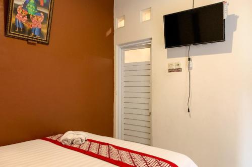 a bedroom with a bed and a flat screen tv on the wall at Grha Vege Jawi Syariah Mitra RedDoorz in Yogyakarta