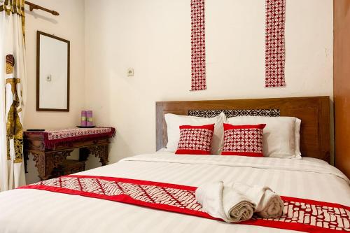una camera da letto con un letto con cuscini rossi e bianchi di Grha Vege Jawi Syariah Mitra RedDoorz a Yogyakarta