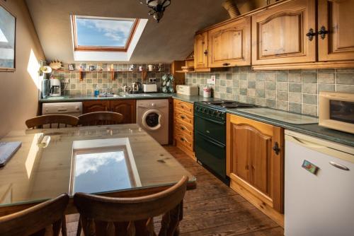 una cocina con armarios de madera y una mesa con sillas. en Atlantic View Cottages en Doolin