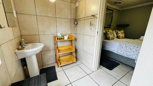 baño pequeño con lavabo y cama en Aspen Guest House NO LOADSHEDDING, en Centurion
