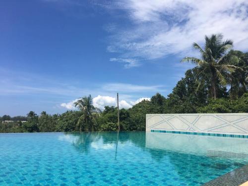una piscina con agua azul y palmeras en 1b pool, Gym, walk to lovely Naiyang Beach en Nai Yang Beach