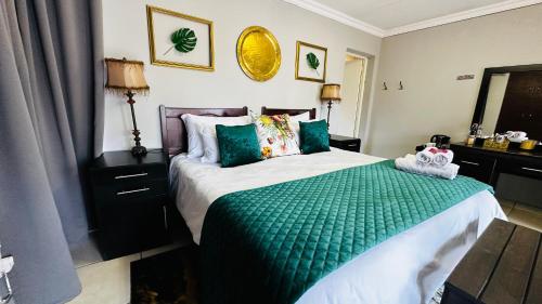 a bedroom with a bed with a green comforter at Aspen Guest House NO LOADSHEDDING in Centurion