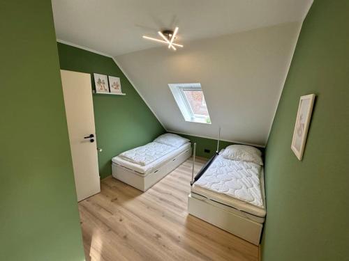 a small room with two beds and a ceiling fan at Haus Zuckersnuut in Dornum