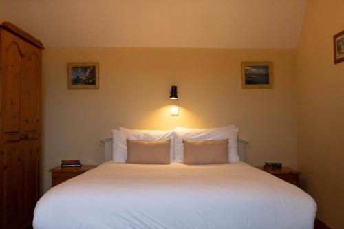 a bedroom with a large white bed with two pillows at Atlantic View Cottages in Doolin
