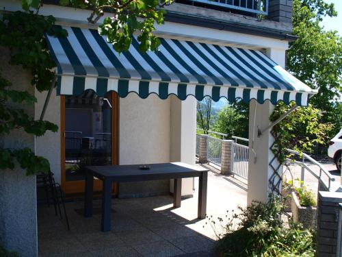 a blue and white awning over a table on a patio at Haus am Hügel in Millstatt