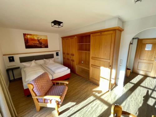 a bedroom with a bed and a chair at Hotel Askania 1927 in Bad Wiessee