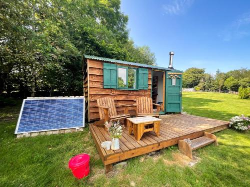 a tiny house with a solar panel on a field at Shire the Shepherd's Hut at Pentref Luxury Camping in Penuwch