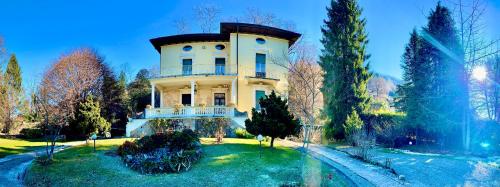 une grande maison au sommet d'un champ arboré dans l'établissement La Villa del Lago, à Ghirla