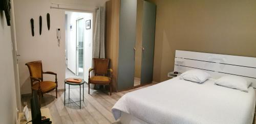 a bedroom with a white bed and two chairs at L'Horizon in Vichy