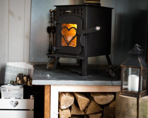 una stufa a legna con un cuore dipinto sopra di Shire the Shepherd's Hut at Pentref Luxury Camping a Penuwch