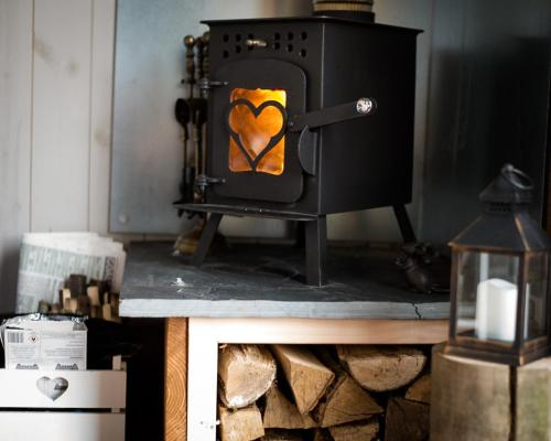 a wood stove with a heart painted on it at Shire the Shepherd's Hut at Pentref Luxury Camping in Penuwch