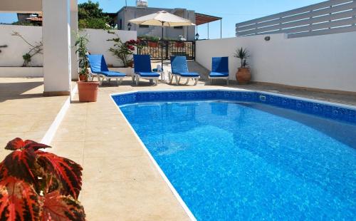 a blue swimming pool with blue chairs and a building at Villa Only 50m To The Sea, Sleeps 12, Polis in Pomos