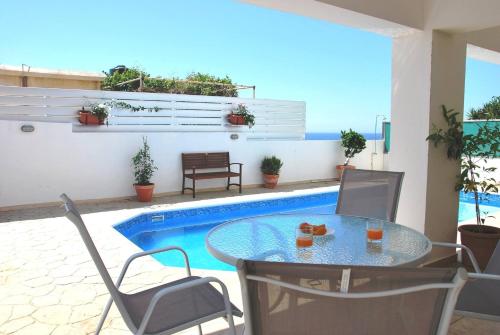 a patio with a table and chairs and a pool at Villa Only 50m To The Sea, Sleeps 12, Polis in Pomos