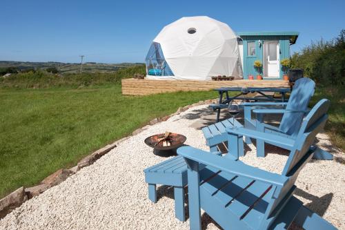 a yurt with blue chairs and a table and a fire pit at The Dome at Mid Auchengowan in Lochwinnoch