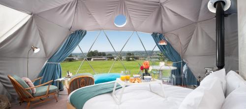 a tent with a bed and a table in it at The Dome at Mid Auchengowan in Lochwinnoch