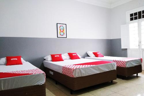 two beds in a room with red pillows on them at OYO Hotel Brás in Sao Paulo