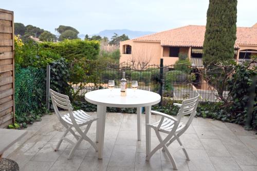 - une table blanche avec 2 chaises et des verres à vin dans l'établissement Aigues Marines YourHostHelper, à Saint-Cyr-sur-Mer
