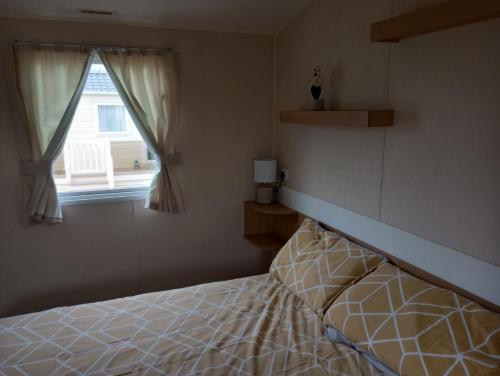 - une chambre avec un lit et une fenêtre dans l'établissement D24 is a 2 bedroom 6 berth caravan close to the beach on Whitehouse Leisure Park in Towyn near Rhyl with decking and private parking space This is a pet free caravan, à Abergele