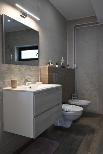a bathroom with a sink and a toilet and a mirror at Casa Erty in Eforie Nord