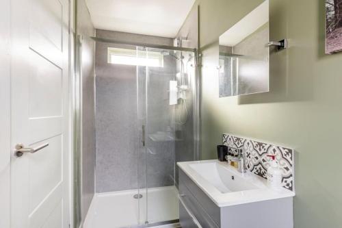 baño blanco con ducha y lavamanos en Cosy and modern 1 bedroom garden house - very dog friendly!, en Tarves
