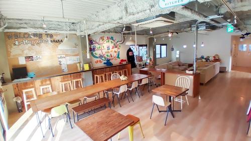 ein Restaurant mit Holztischen und -stühlen in einem Zimmer in der Unterkunft USJに一番近いゲストハウス J-Hoppers Osaka Universal in Osaka