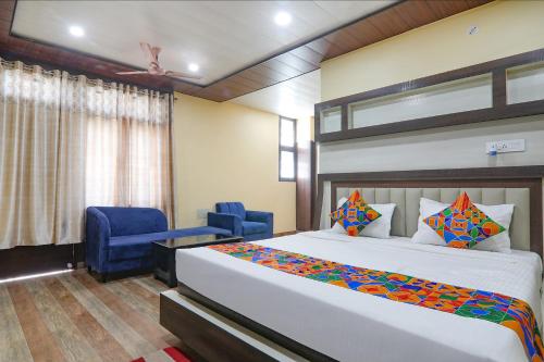 1 dormitorio con 1 cama y 2 sillas azules en FabHotel Saumendra, en Varanasi