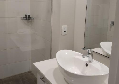 y baño blanco con lavabo y ducha. en Regency Apartment en Pretoria