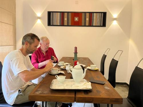 two men sitting at a table in a restaurant looking at their cell phone at Villa Touch of Dutch in Tangalle