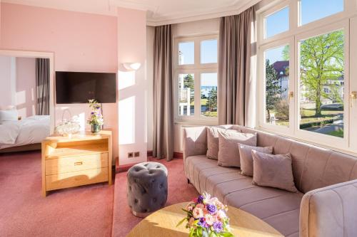 a living room with a couch and a large window at Hotel Residenz Waldkrone Kühlungsborn in Kühlungsborn