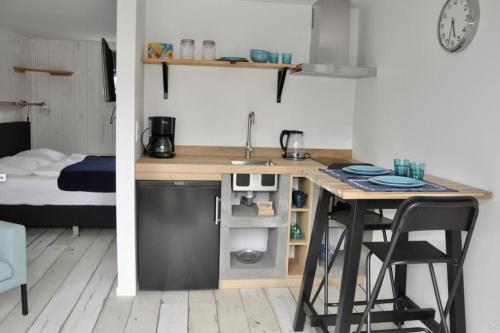 a kitchen with a table and a sink and a bed at Anna, strandhuisje dichtbij zee & strand! in Callantsoog