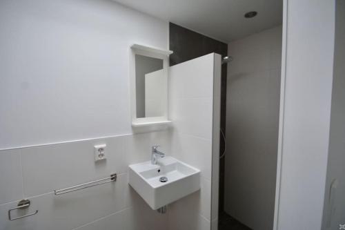 a white bathroom with a sink and a mirror at Anna, strandhuisje dichtbij zee & strand! in Callantsoog