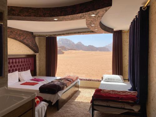 two beds in a room with a view of the desert at Wadi Rum Khalid luxury camp in Wadi Rum