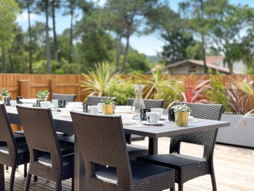 Une table à manger et des chaises sont disponibles sur la terrasse. dans l'établissement Appartement Céleste - Villas Lake and Sea, à Seignosse