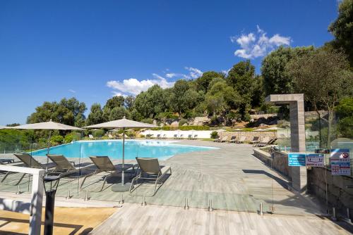 une grande piscine avec chaises et parasols dans l'établissement Domaine d'Arca-Porto-Vecchio-T2-2 personnes- Hugo 6, à Porto-Vecchio