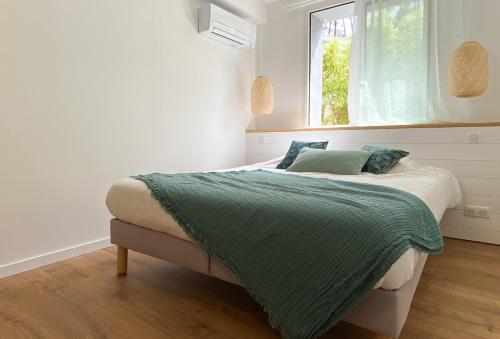 una camera da letto con un letto con una coperta verde e una finestra di Appartement Océane - Villas Lake and Sea a Seignosse
